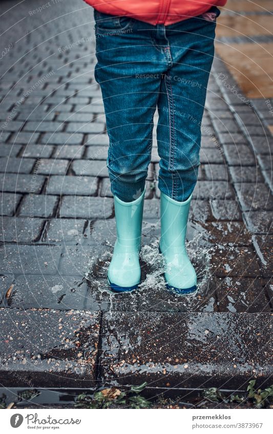 Kind springt in Pfütze und kommt an einem regnerischen, düsteren Herbsttag herein regnet im Freien wenig saisonbedingt fallen Kindheit schön Wetter außerhalb