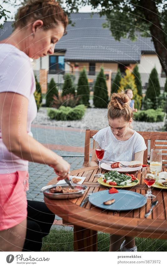 Familie isst während des Sommerpicknicks im Freien in einem Hausgarten zu Abend heimwärts Festessen habend Picknick Lebensmittel Mann Zusammensein Frau Kind