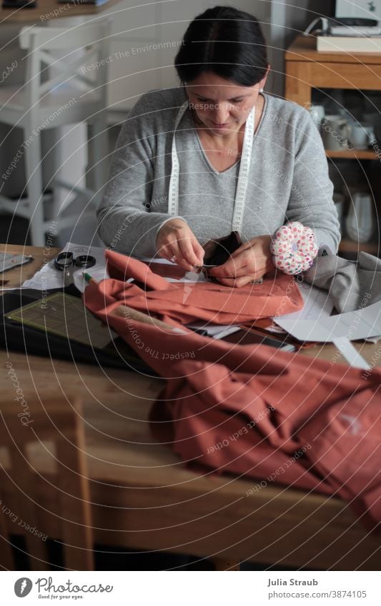 Hobbynäherin zuhause am Esstisch bei der Arbeit Nähen Handarbeit handarbeiten abstecken Schneidern Maßband Kreativität Hobbys Nadelkissen Stoff Muster Schere