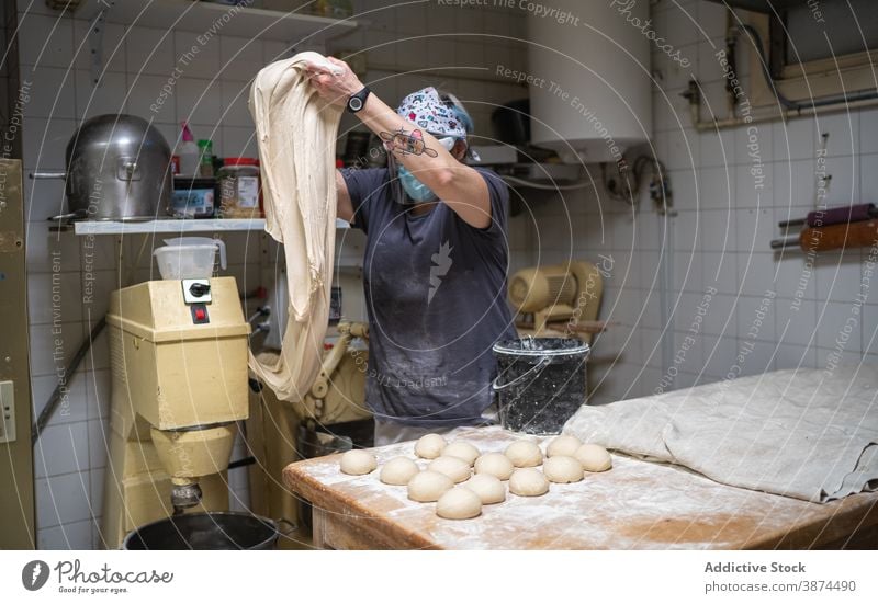 Frau knetet Teig in der Backstube Brot Bäckerei roh Arbeit kneten Teigwaren vorbereiten Küche Mundschutz neue Normale Koch Lebensmittel Küchenchef frisch