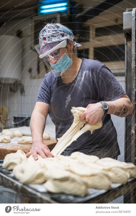 Bäcker bereitet Teig zum Backen vor Teigwaren Bäckerei Brot Frau vorbereiten ungekocht Form rund Mundschutz Schutzschild Tisch Küche Arbeit kulinarisch roh Koch