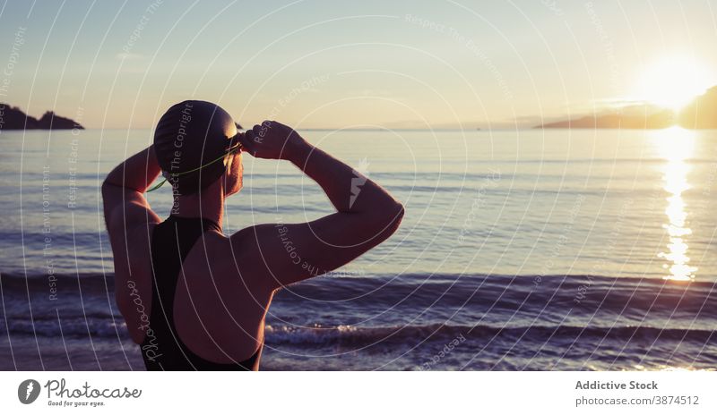 Schwimmer in Badeanzug und Schwimmbrille in der Nähe von Meer Badebekleidung Schutzbrille Meeresufer Sonnenuntergang Training genießen professionell passen MEER