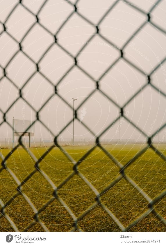 Menschenleeres Fußballfeld in Coronazeiten menschenleer fussballplatz training rasen wiese grün winter grau nebel zaun lock down corona coronavirus sport verbot