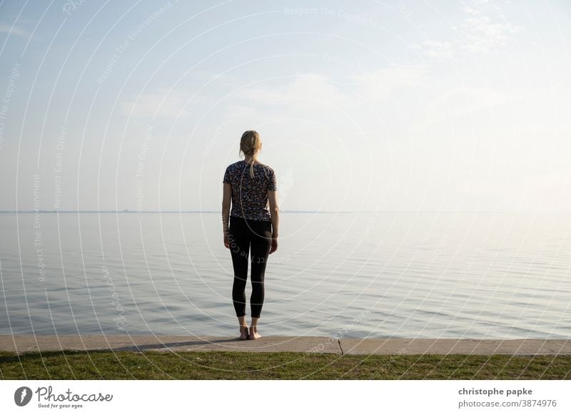 Junge Frau steht vor Meer Bodden Ferien & Urlaub & Reisen Erholung nachdenklich Ruhe Wasser Horizont ausblick Küste Natur Himmel Ferne Ostsee Menschenleer