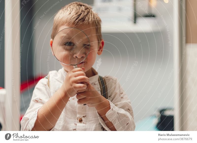 Süßer kleiner Junge mit einer Lupe in der Hand schön Pflege Kaukasier Kind Kindheit Konzept Neugier neugierig neugieriger Junge niedlich Bildung Gesicht finden