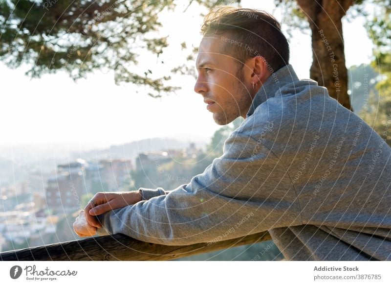 Nachdenklicher Mann rastet auf einem Hügel in der Nähe der Stadt nachdenklich besinnlich Hipster nachdenken träumen Denken Natur lässig Windstille