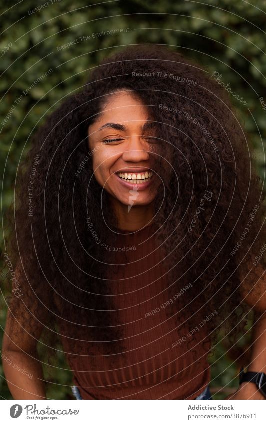 Glückliche ethnische Frau im grünen Garten charmant Lächeln natürlich Schönheit offen krause Haare Afro-Look Frisur Park schwarz Afroamerikaner jung heiter