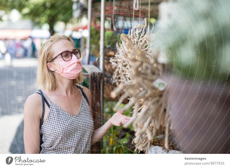 Lässige Frau beim Einkaufen im Freien an Marktständen mit Fasenmasken zum Schutz vor der Coronavirus-Pandemie in München, Deutschland Mundschutz Lifestyle