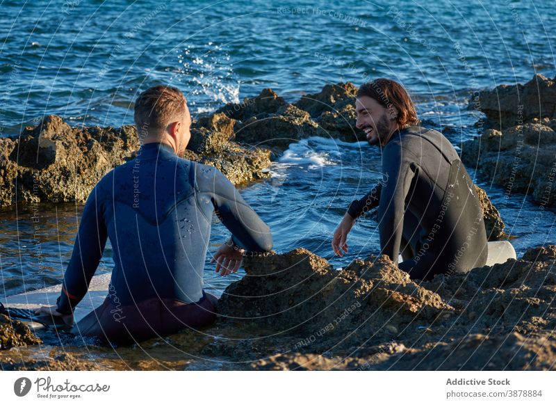 Männer mit Surfbrettern am felsigen Ufer Surfer MEER Zusammensein Freund Wasser Lachen Freundschaft Neoprenanzug Meer Glück Natur Freiheit Sommer