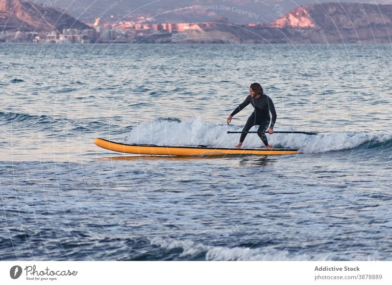 Mann im Neoprenanzug auf Paddleboard im Meer Paddelbrett Surfer Reihe Brandung SUP MEER Training männlich Sommer Sport Wasser Sonnenuntergang Natur genießen