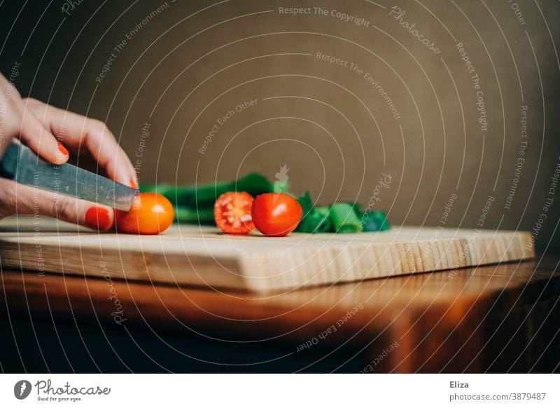 Frauenhände schneiden Tomaten auf einem Schneidebrett. Frühlingszwiebeln Zubereitung Essen kochen frisch Hände Küche Essen zubereiten Messer Lebensmittel