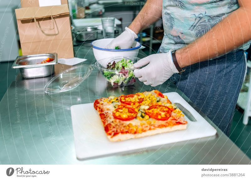 Unbekannter Koch bereitet Takeaway-Bestellungen vor unkenntlich Orden Imbissbude Verpackung Salatbeilage Handschuhe Hygiene sichere Lebensmittel Großküche Paket