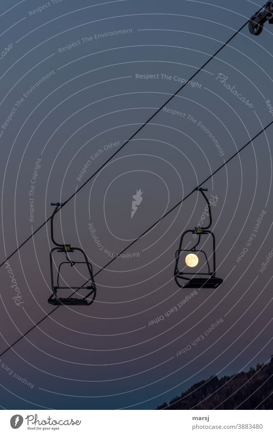 Der Herr mit Mondgesicht im Sessel Nr. 34 wartet vergebens. Lockdown legt sogar die Sessellifte still. Vollmond Winterurlaub Außenaufnahme