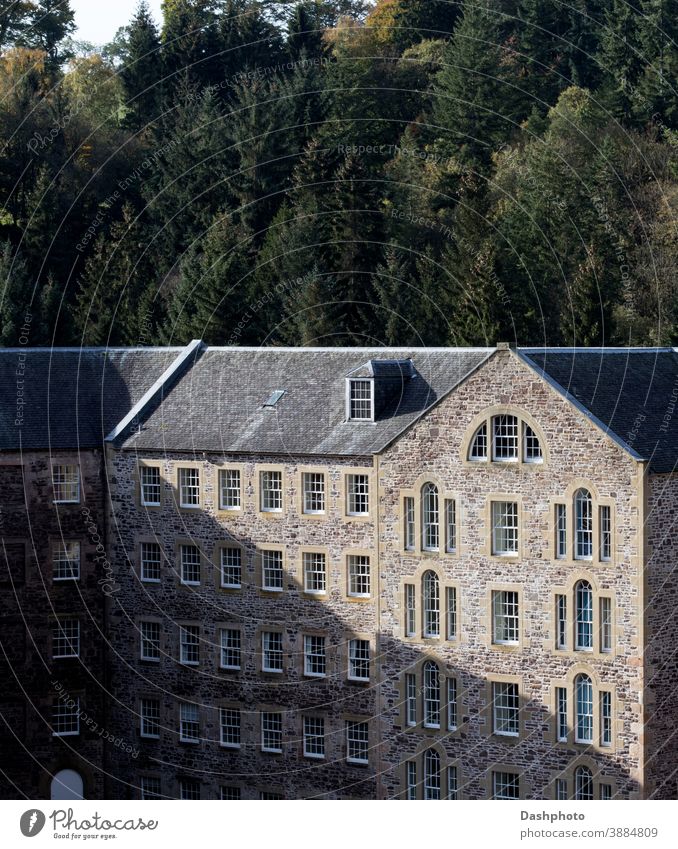 Altes stillgelegtes Mühlengebäude in New Lanark Village Schottland in der Herbstsonne Dorf konvertiert Gebäude Stein Mauerwerk Maurerhandwerk Schatten Baum