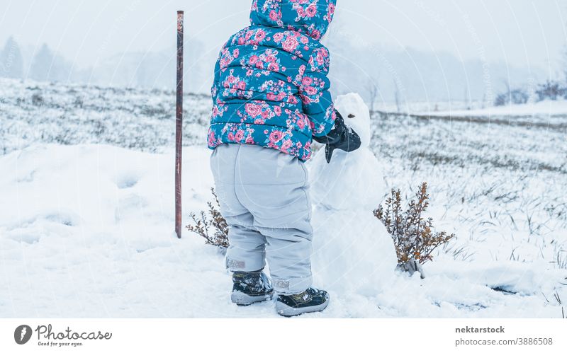 Kind baut Schneemann im Freien Rückansicht in voller Länge 1 Mensch nicht erkennbare Person mit Kapuze Stehen Gebäude Kindheit wachsen lernen Aktivität