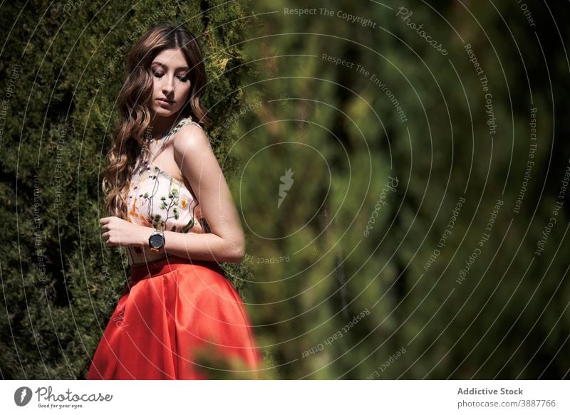 Elegante Frau im Kleid zu Fuß entlang Weg im Park Anmut Garten elegant Spaziergang charmant Vorschein Stil Outfit gewelltes Haar lange Haare Model trendy