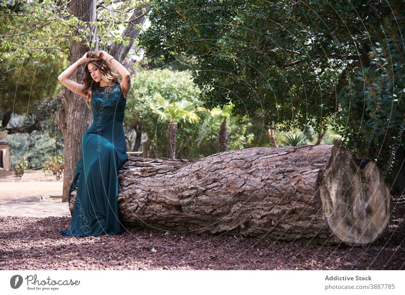 Zarte Frau in langem smaragdgrünem Kleid im Wald Anmut elegant Smaragd Wälder Natur ruhig verträumt sorgenfrei Baum Kofferraum sitzen maxi jung Stil Waldgebiet