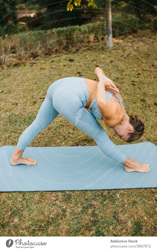 Frau tut Yoga-Pose mit Gebet Hände hinter dem Rücken Park gebundene, gedrehte Halbmond-Longe Halbpyramide Gebetshände ardha parsvottanasana Asana Namaste stehen