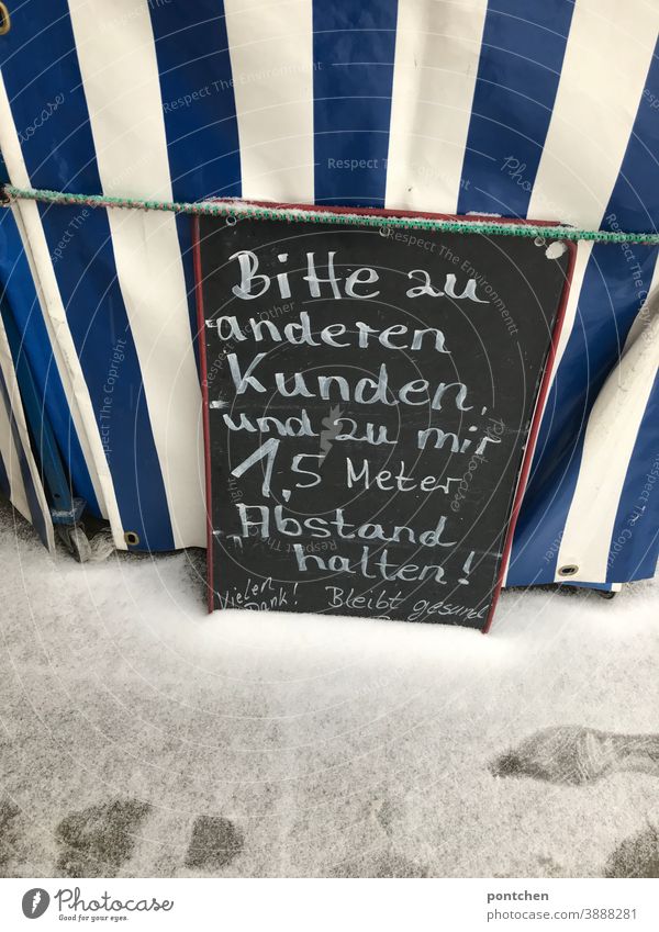 Tafel mit der Aufschrift  1,5 Meter Abstand halten vor einem Obststand. Covid-19 corona tafel hinweis abstand schutz prävention ansteckung kunde kreide wörter