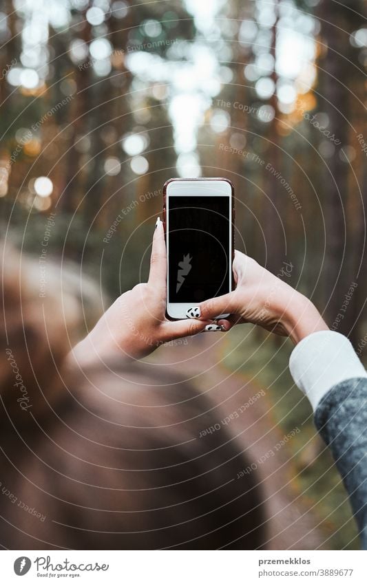 Junge Frau fotografiert mit einem Smartphone während eines Waldspaziergangs in den Sommerferien aktiv Aktivität Ausflugsziel genießen Erkundung Wanderung