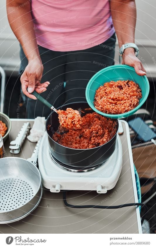 Frau stellt in den Sommerferien auf dem Campingplatz Reisgericht mit Tomatensauce in eine Schüssel Mittagessen Outdoor-Küche heiß Topf Speise Koch Mahlzeit