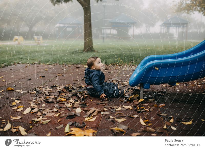 Kleinkind spielt auf dem Spielplatz Herbst authentisch Winter fallen Spielen Sliden Park Kindergarten Außenaufnahme Freude Farbfoto Tag Kindheit