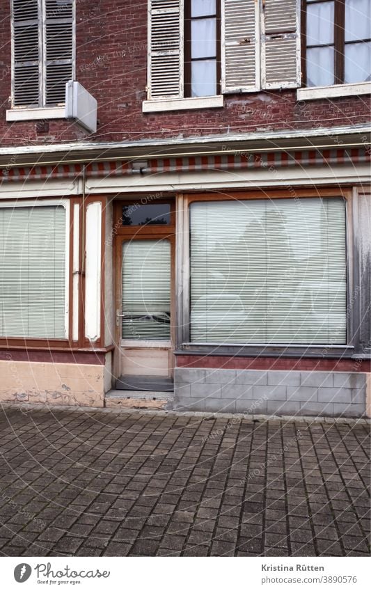 aufgegebenes geschäft geschlossen verlassen schaufenster fassade zu architektur rollos jalousie sichtschutz laden ladenlokal gebäude einzelhandel tür eingang