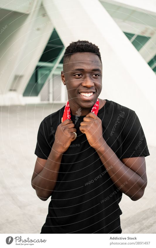 Fröhlicher schwarzer Mann mit Kopftuch in der Stadt urban Straße heiter gutaussehend cool Frisur Afro-Look krause Haare männlich ethnisch Afroamerikaner rot