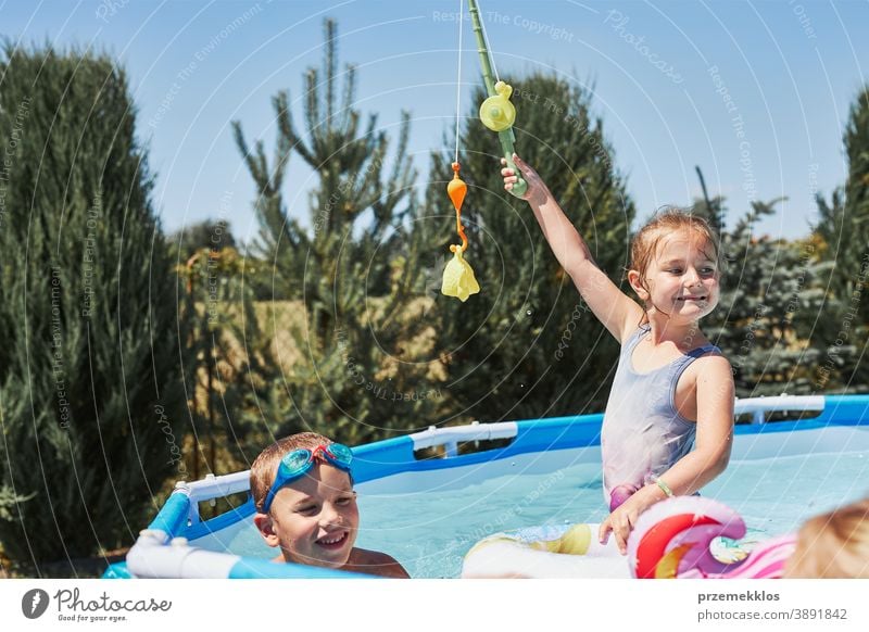 Kinder spielen mit Angelrutenspielzeug in einem Pool im Hausgarten authentisch Hinterhof Kindheit Familie Spaß Garten Fröhlichkeit Glück Freude Lachen Lifestyle