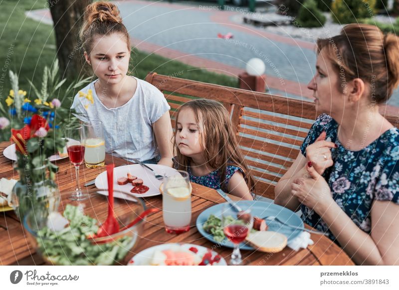 Familie isst während des Sommerpicknicks im Freien in einem Hausgarten zu Abend heimwärts Festessen habend Picknick Lebensmittel Mann Zusammensein Frau Kind