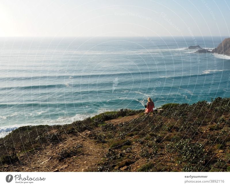 junge Frau, die draußen in der Sonne an ihrem Laptop mit Blick auf das Meer arbeitet Remote-Job digitaler Nomade Heimarbeitsplatz Digitalisierung