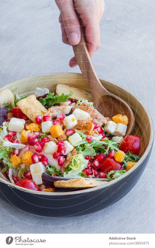 Crop Person serviert leckeren Caesar-Salat Salatbeilage Schalen & Schüsseln festlich Abendessen Käse Granatapfel Hähnchen grün Cracker Samen Bestandteil Koch