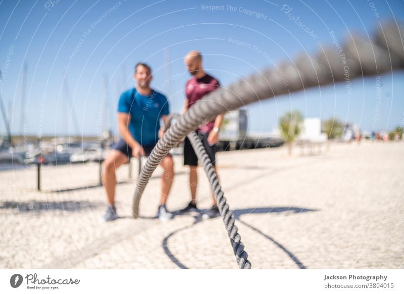 Kampfseile im Freien von Mann und seinem Personal Trainer verwendet Drahtseile Trainerin Übung Seile Schlacht Kreuzpassung Sportler Schwitzen Männer Ausdauer