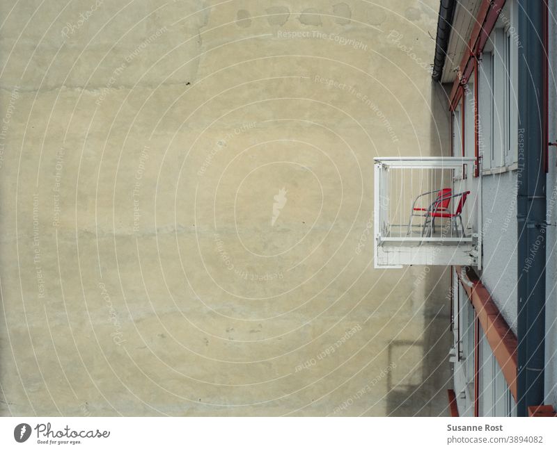 Blick auf einen Balkon mit 2 Stühlen in einem Hinterhof Wand orange urban Fassade Stadt Gebäude Mauer Stuhl Architektur Tristesse Bauwerk städtisches Leben