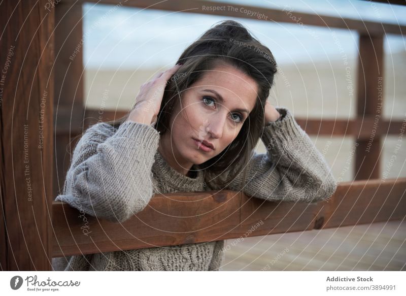 Zärtliche Frau auf Strandpromenade am Strand Pullover Zaun Spazierweg Promenade Windstille Gelassenheit allein schön Erholung anlehnen lässig ruhen ruhig Stil