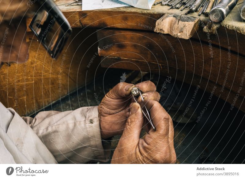 Juwelier bei der Arbeit mit Diamanten in der Werkstatt professionell Mann Goldschmied Stein Pinzette Fähigkeit reif Werkzeug männlich Meister Hobelbank Schmuck