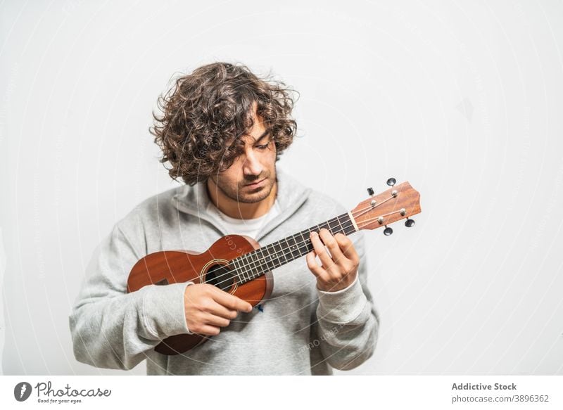 Fröhlicher Mann spielt Ukulele Gitarre spielen heiter Musiker ausführen positiv Instrument Glück jung ethnisch hispanisch männlich Melodie Lifestyle Gesang