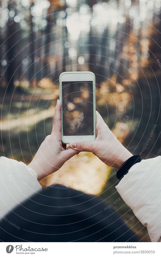 Frau fotografiert Waldlandschaft mit Smartphone während einer Reise an einem sonnigen Herbsttag Rücken Funktelefon Ausflugsziel erkunden fallen Mädchen