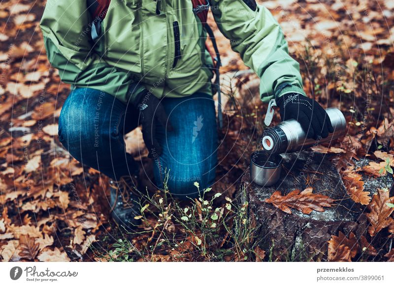 Frau mit Rucksack macht während einer Herbstreise am kalten Herbsttag Pause und gießt ein heißes Getränk aus der Thermoskanne im Freien Ausflugsziel wandern