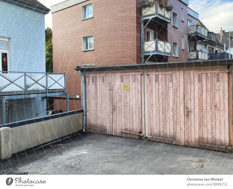 Nachbarschaften | Hinterhof mit Blick auf zwei alte rosafarbene Garagentore und die Fenster und Balkone der Mehrfamilienhäuser dahinter Mietshäuser Häuser