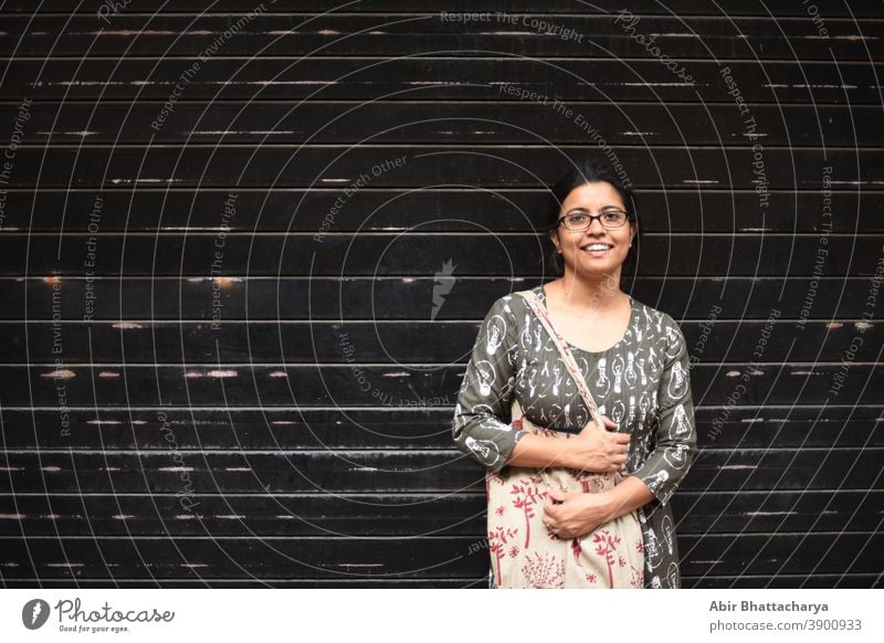 Porträt einer indisch-bengalischen brünetten Frau vor einer Wand/Metallic-Tor/ schwarz strukturierter Hintergrund. Indischer Lebensstil Schauspielerin