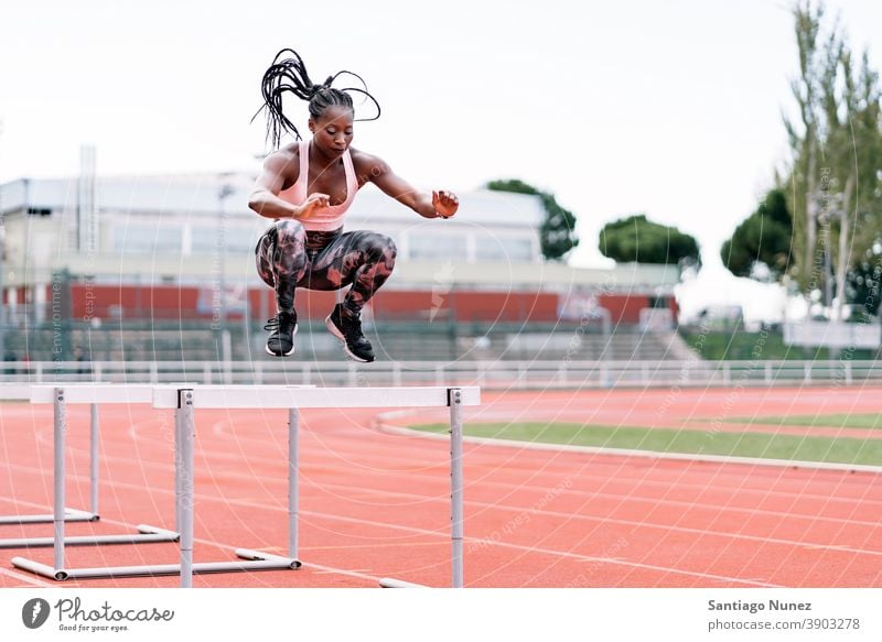 Afrikanisch-amerikanischer Athlet Sprinter springt über eine Hürde entschlossen muskulös springen Afro-Look Amerikaner Beginn Ehrgeiz Motivation Bewegung