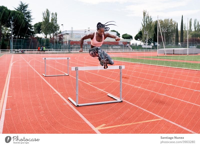 Afrikanisch-amerikanischer Athlet Sprinter springt über eine Hürde entschlossen muskulös springen Afro-Look Amerikaner Beginn Ehrgeiz Motivation Bewegung