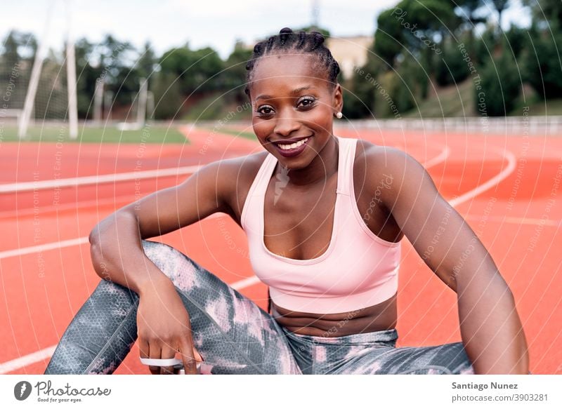 Athlet Sprinter sitzend auf der Leichtathletikbahn ethnisch Afro-Look afroamerikanisch Bahn Zug Training Sportbekleidung Athletik Frau Läufer rennen Konkurrenz