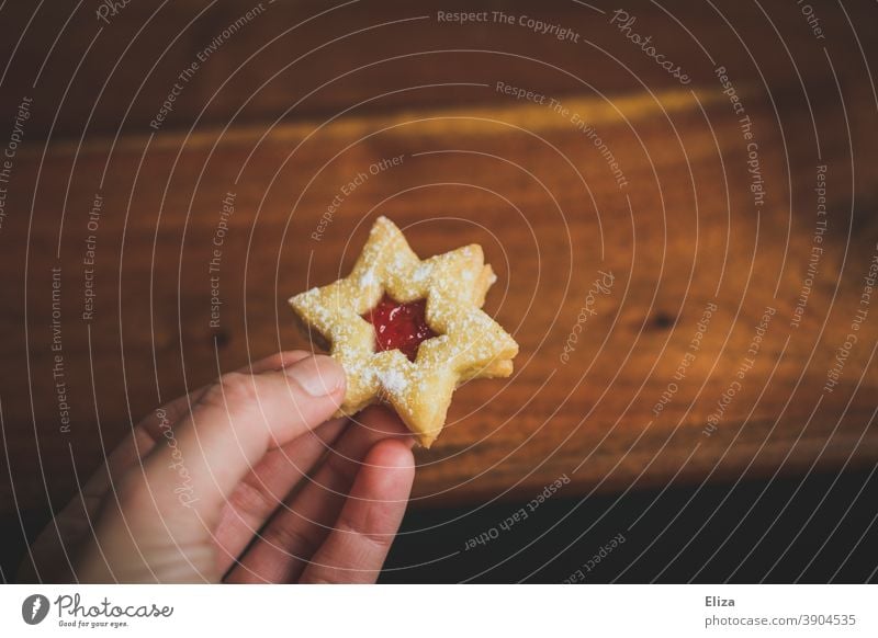 Frau hält ein Spitzbuben Plätzchen in Sternform naschen Weihnachten Weihnachtsplätzchen Weihnachtsnascherei Weihnachten & Advent Backwaren süß Hand weiblich