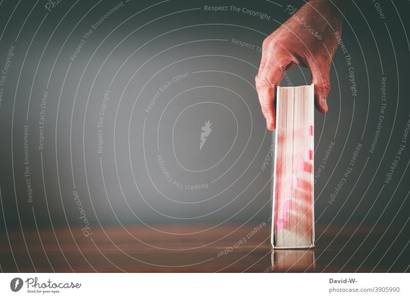 Griff zu einem Buch beklebt mit Haftmarker Lernen Studium Bildung Wissen lernen Schule fleißig Hand greifen Notizen Vorbereitung lesen Platzhalter Lesestoff