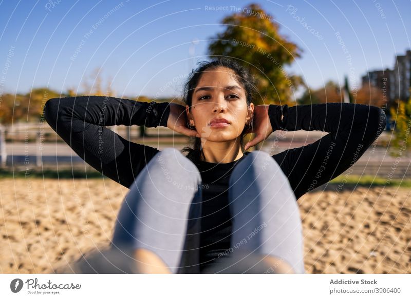 Sportliche Frau macht Bauchpressen auf dem Sportplatz Unterleib knirschen Bauchmuskeln Training passen calisthenics Bestimmen Sie ethnisch Wohlbefinden