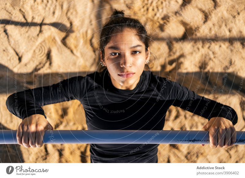 Entschlossene Frau macht Übungen am Reck calisthenics horizontal Bar Sportpark stark Bestimmen Sie Athlet Training ethnisch üben Fitness Sportbekleidung