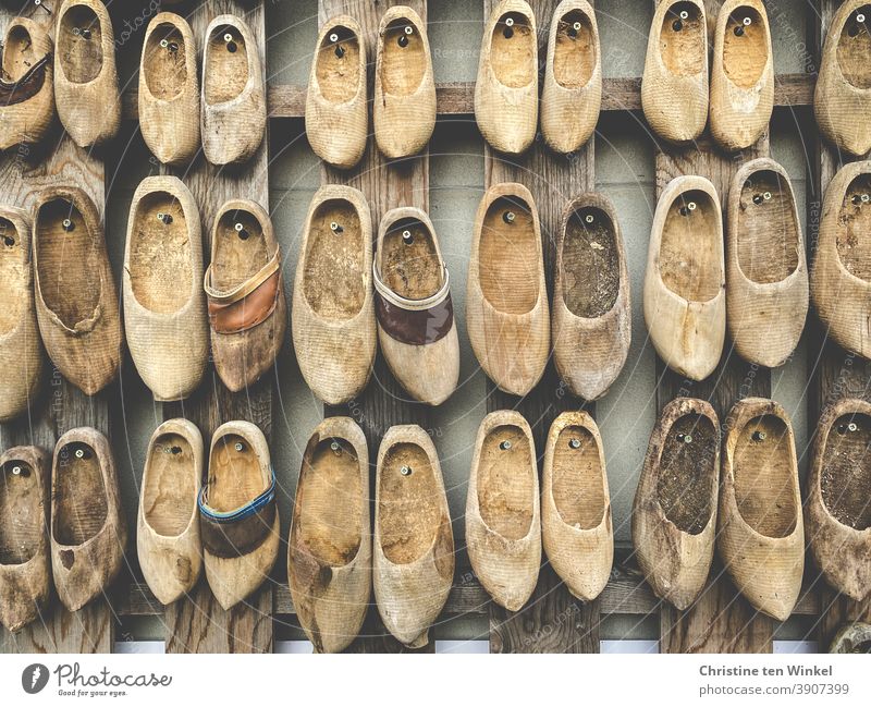 Ganz viele alte Holzschuhe, Klompen, Münsterländer Holzklumpen sind dekorativ an einer Wand befestigt gebraucht kaputt Dekoration kreativ Kreativität