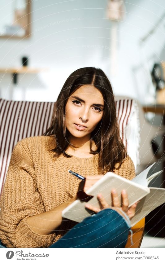 Fröhliche Frau macht sich Notizen in einem Notizbuch zur Kenntnis nehmen Notebook schreiben Tagebuch Lächeln Wochenende genießen heimwärts Notizblock Outfit